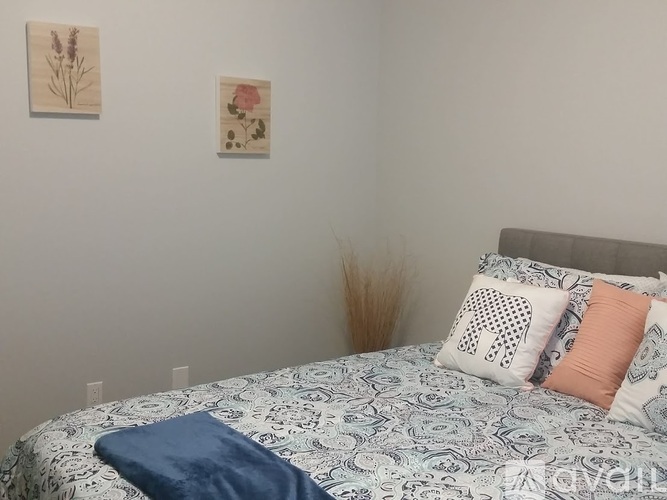 A bed with a blue blanket and pillows with a pattern of a giraffe and other designs.