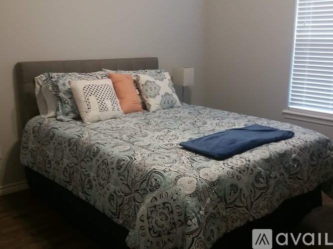 A bed with a grey headboard and a blue and white patterned comforter.