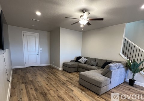 A living room with a grey couch and a ceiling fan.