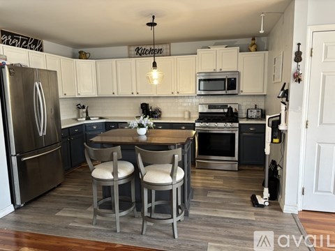 A kitchen with a table and chairs in front of a refrigerator.