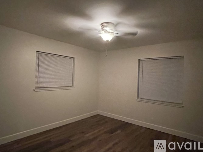 A room with a ceiling fan and two windows.