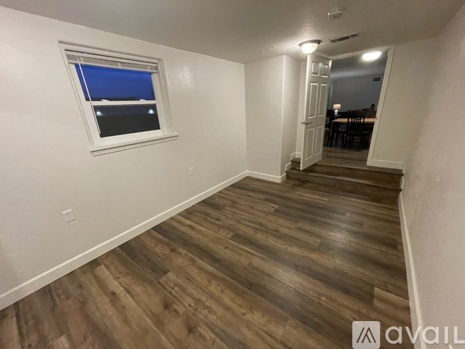 A room with wooden flooring and a window with a blue cover.