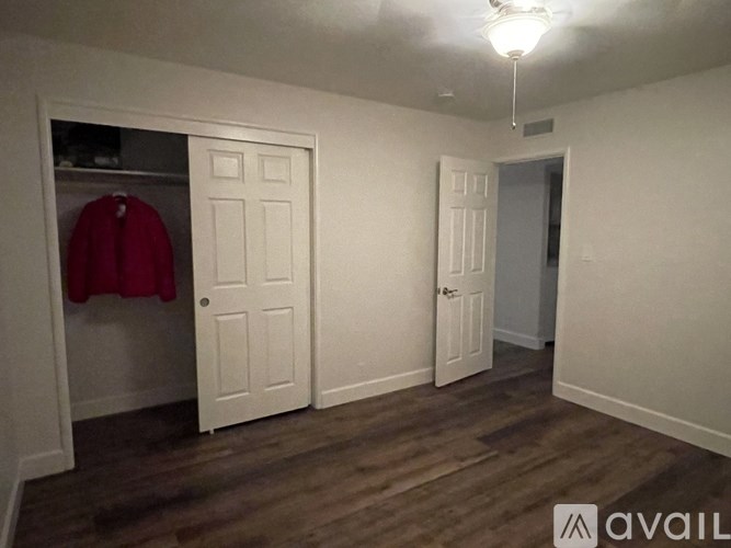A room with a coat hanging on the door and a wooden floor.