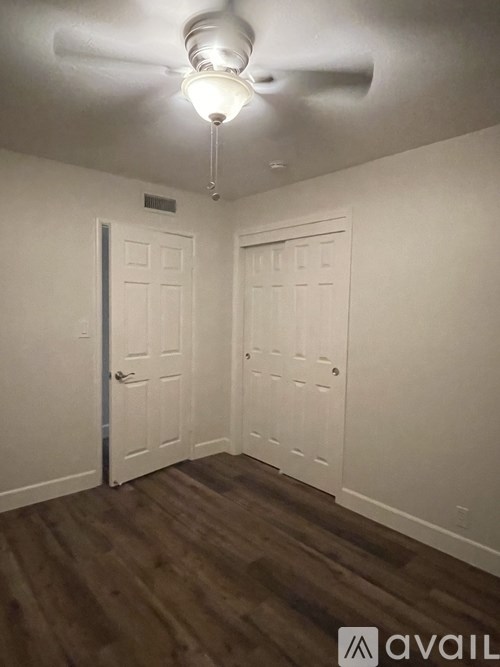 A room with a ceiling fan and two doors.