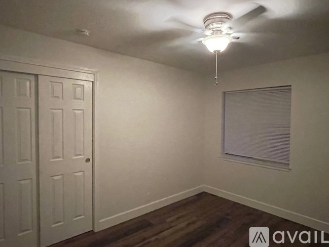 A room with a ceiling fan and a window with blinds.