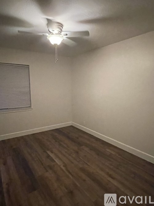 A room with a ceiling fan and wooden flooring.