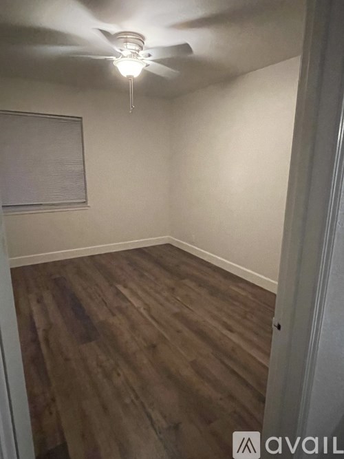 A room with a ceiling fan and wooden flooring.
