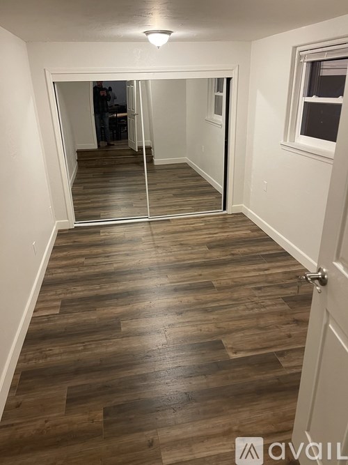 A hallway with a wooden floor and a white door.