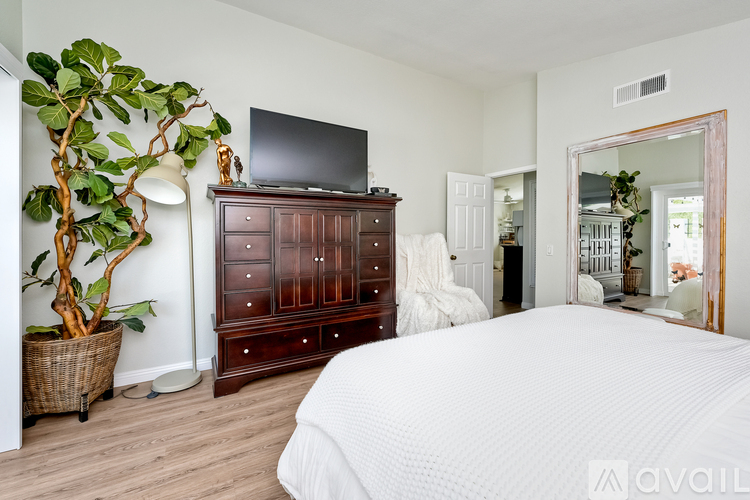 A bedroom with a large bed, a wooden dresser, and a mirror.