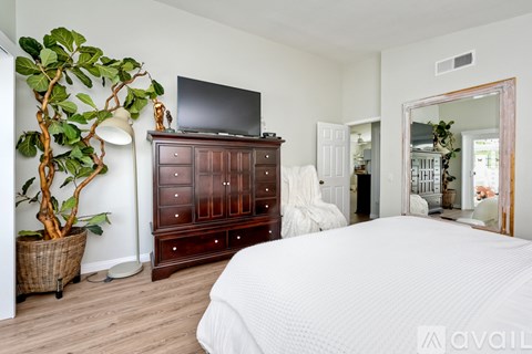 A bedroom with a large bed, a wooden dresser, and a mirror.