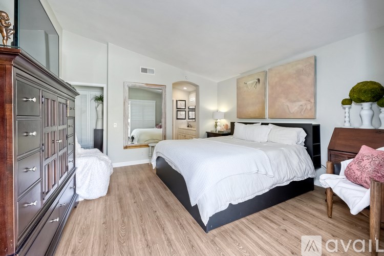 A bedroom with a large bed and wooden floors.