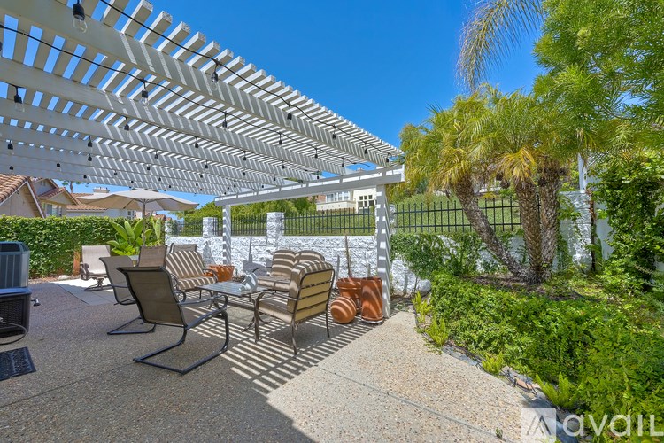 A patio with a white pergola and several chairs.