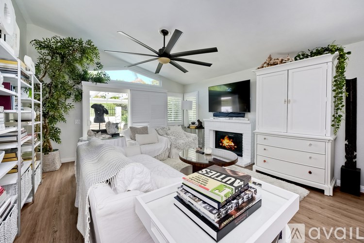 A white bedroom with a bed, dresser, and a ceiling fan.