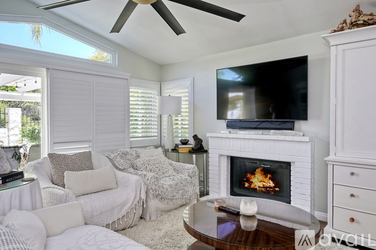 A living room with a fireplace and a television on the wall.