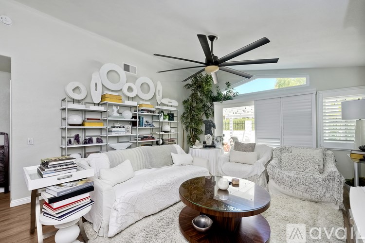 A living room with a white couch, a coffee table, and a ceiling fan.