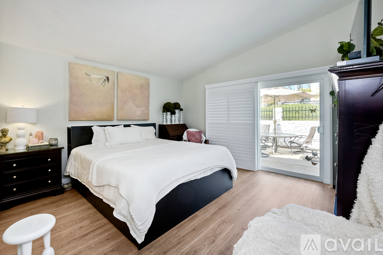 A bedroom with a large bed, a nightstand with a lamp, and a painting on the wall.