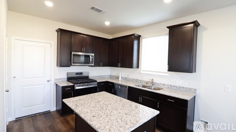 A kitchen with dark wood cabinets and a granite countertop.
