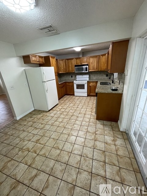 A kitchen with white appliances and wooden cabinets.