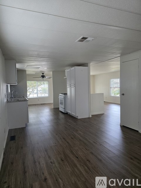 A kitchen area with white cabinets and a wooden floor.