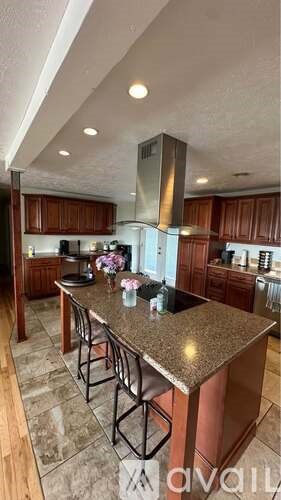 A kitchen with a granite countertop and bar stools.