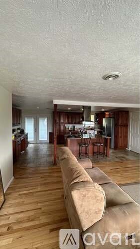 A living room with a couch and a kitchen in the background.