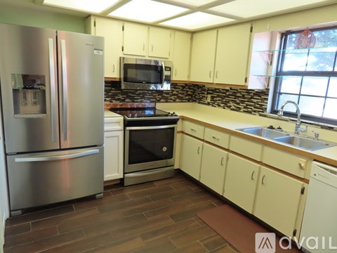 A kitchen with a stainless steel refrigerator and a stove top oven.