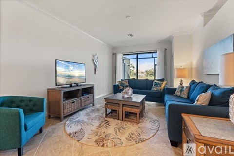 A living room with a green sofa, a wooden coffee table, and a television on a wooden stand.