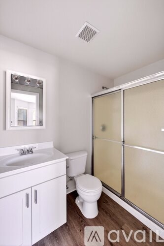 A white bathroom with a toilet, sink, and mirror.