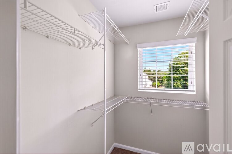 A room with white walls and a window with blinds.