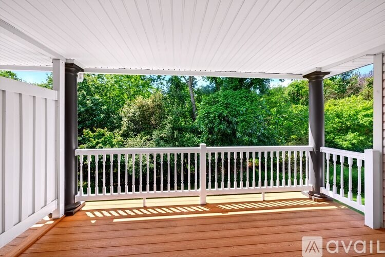 A wooden deck with a white railing and pillars.