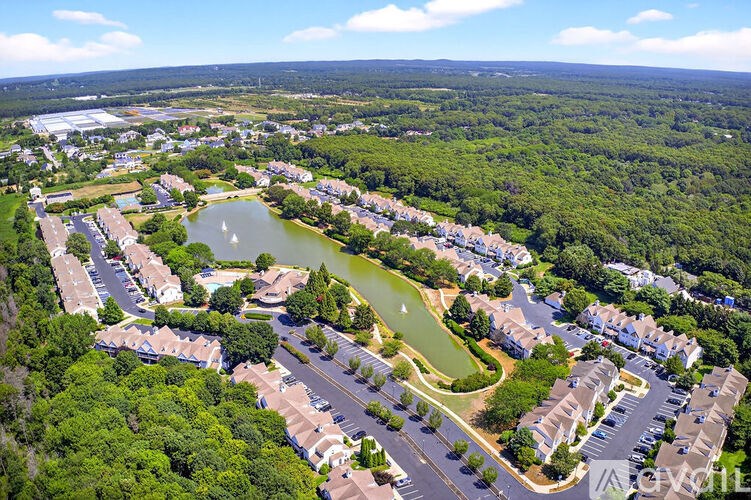 A bird's eye view of a residential area with a lake and greenery.
