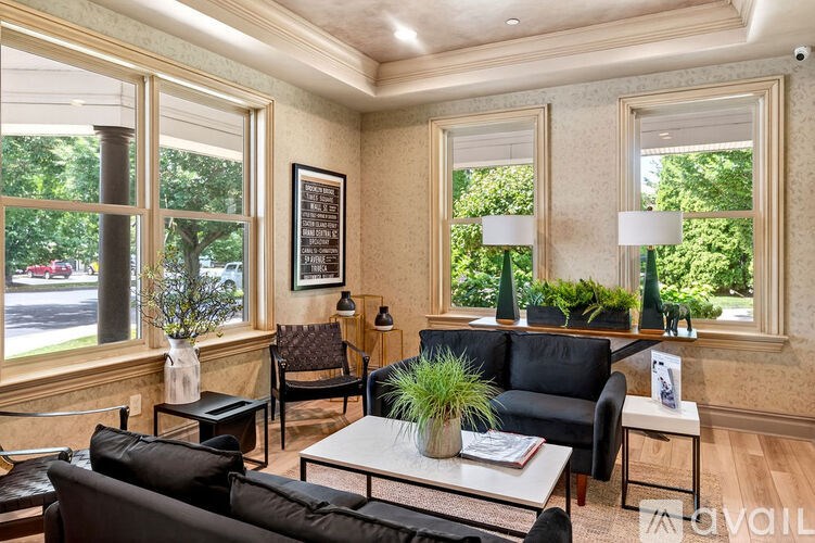 A living room with a black couch, a white coffee table, and a large window.