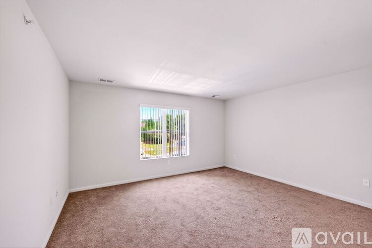 A room with a window that has a view of a fence and trees outside.