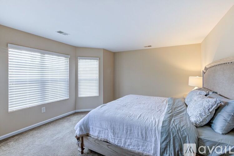 A bedroom with a bed, pillows, and a lamp.