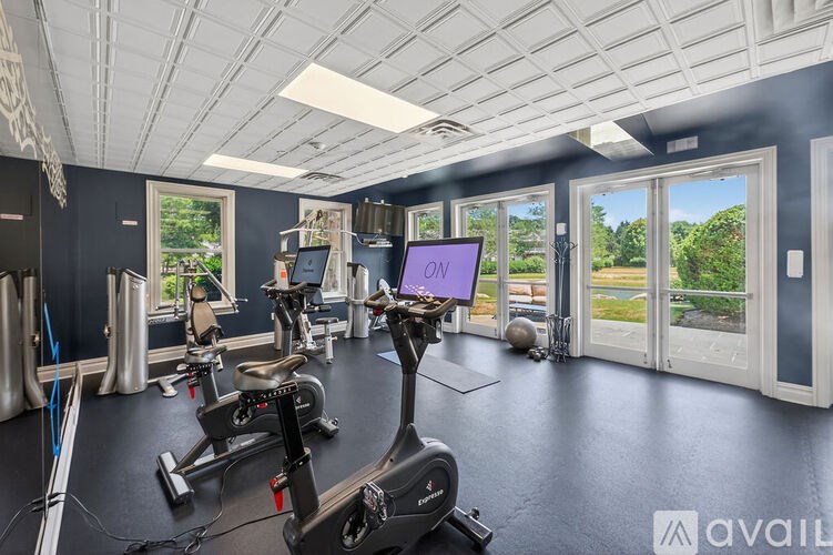 A gym with exercise equipment and a view of the outdoors through the windows.