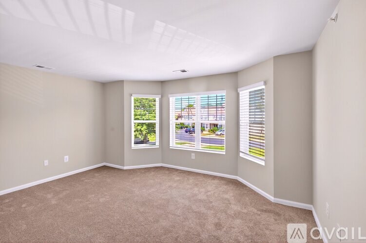 A room with a carpeted floor and two windows with blinds.