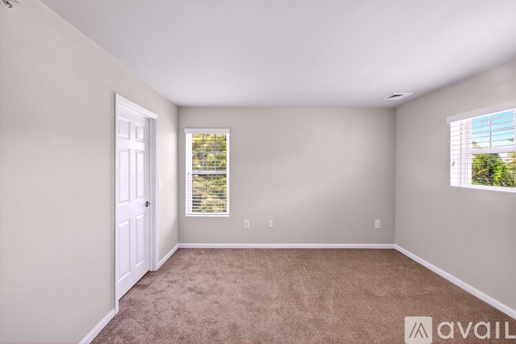 A room with a carpeted floor and a window with blinds.