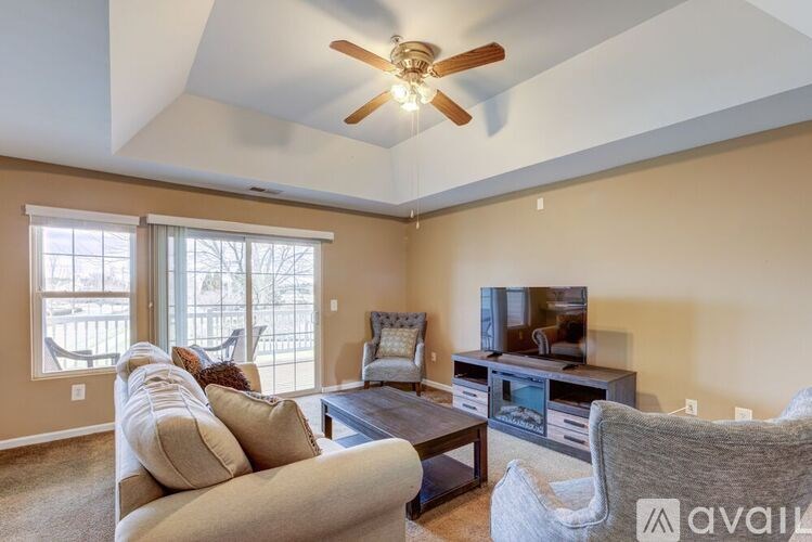 A living room with a television, couch, and a ceiling fan.
