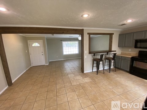 A kitchen area with tile flooring and a counter with a microwave and oven.