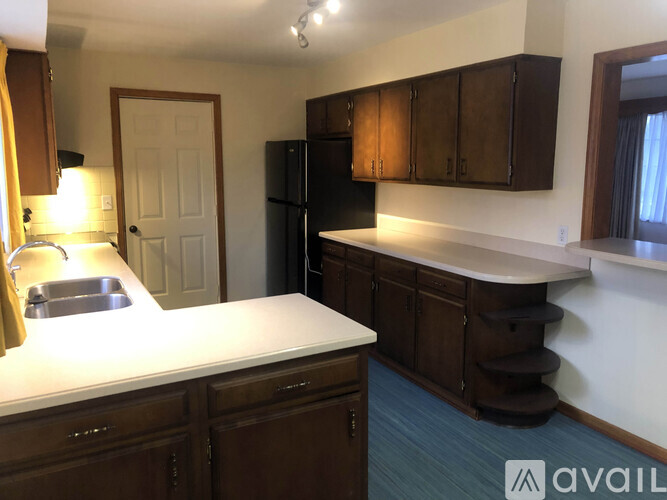 A kitchen with brown cabinets and a black refrigerator.