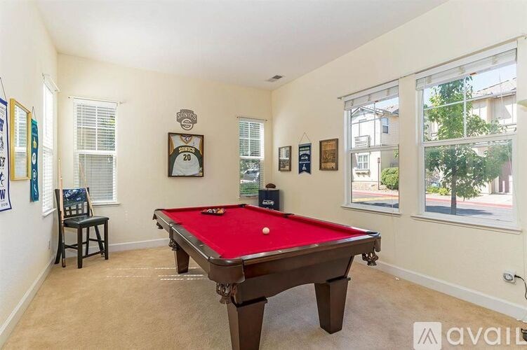 A pool table in a room with a chair and pictures on the wall.