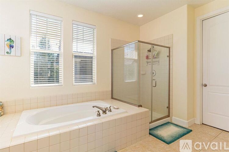 A bathroom with a white tub and a glass shower stall.