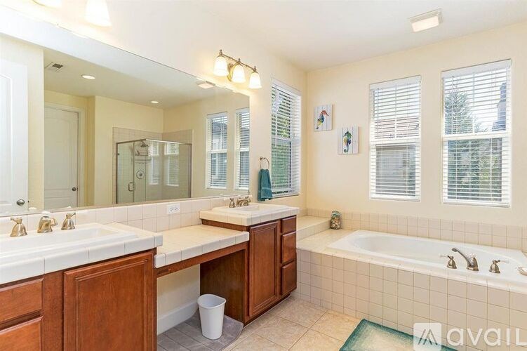 A bathroom with a tub, sink, and mirror.