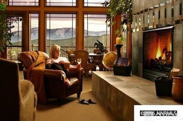 A woman is sitting on a couch in a room with a fireplace.