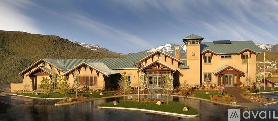 A large house with a green roof and a mountain in the background.
