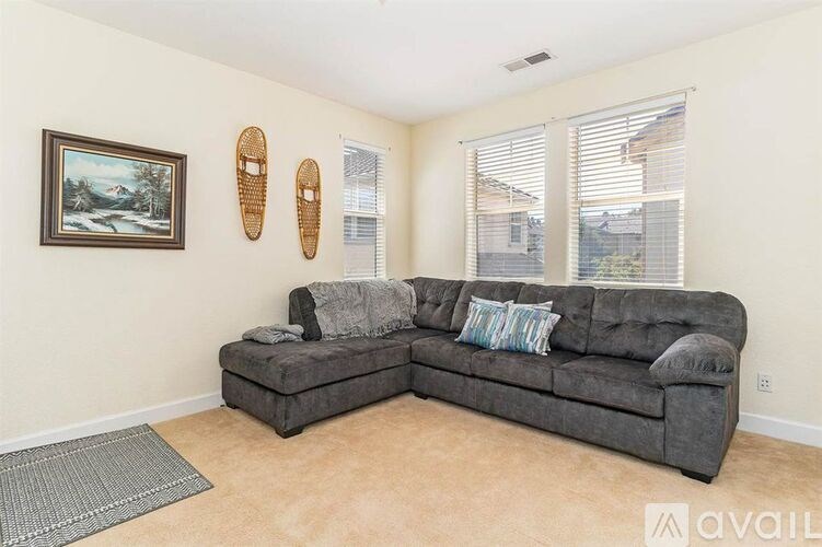 A living room with a grey couch and a painting on the wall.