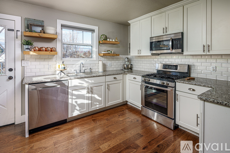 A kitchen with white cabinets and a wooden floor.