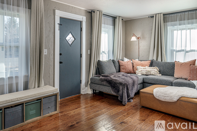 A living room with a grey couch and a grey blanket on it.