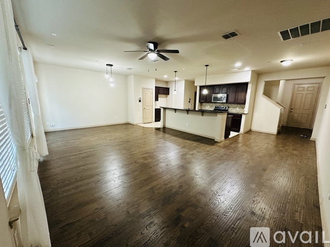 A spacious room with wooden floors and a ceiling fan.