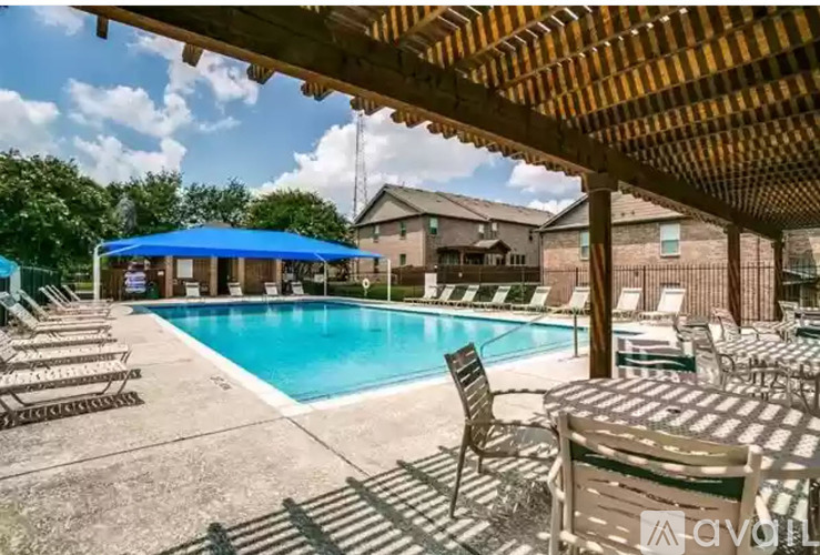 A pool area with sun loungers and a blue canopy.